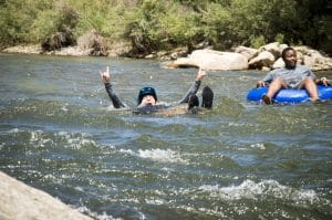 person floating down river with rock hand signs