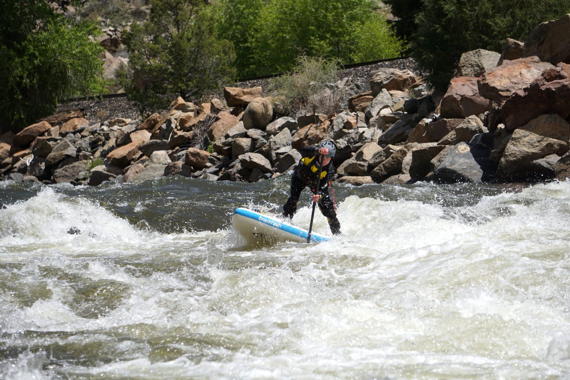 Person paddleboarding in a rapid