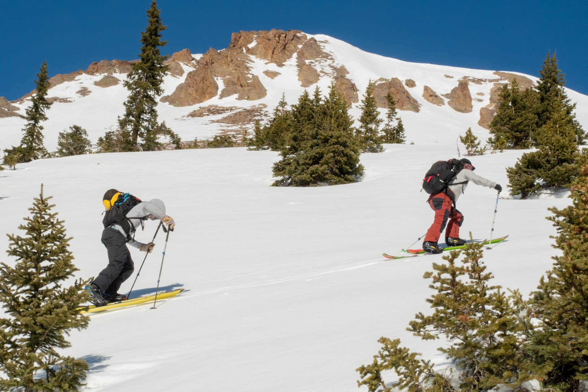 Two backcountry skiers skinning up a hill