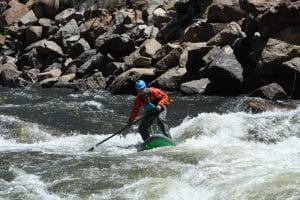 Paddleboarder standing in a river rapid