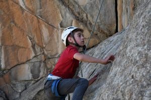 child wearing a helmet rock climbing