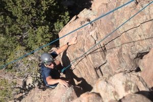 person rock climbing with a helmet and ropes