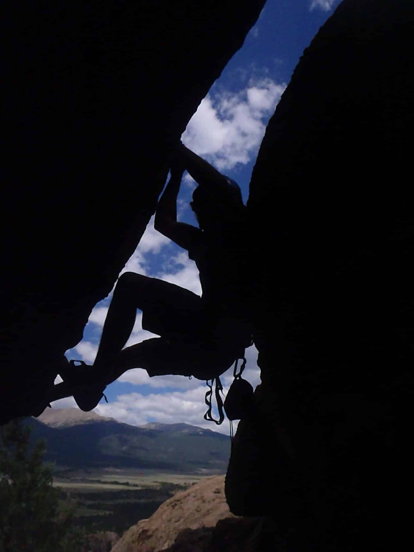 Dark photo of person climbing between two rocks