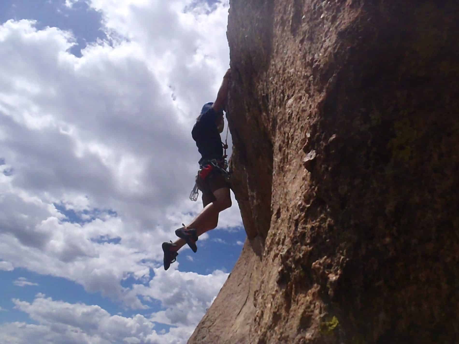 Person hanging off of rock wall